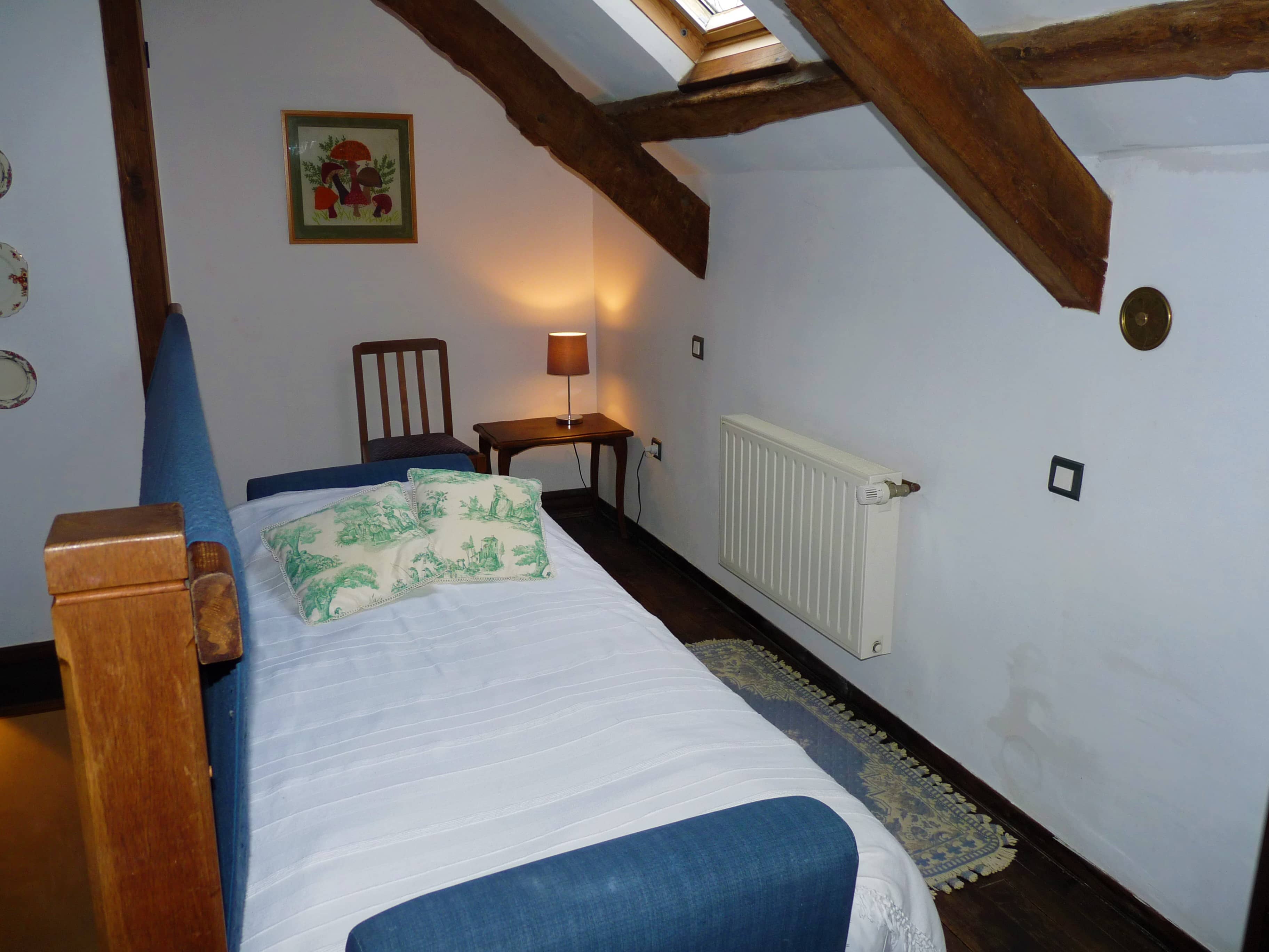 Spacious and comfortable bedroom of La Julerie cottage in Brittany, France, with a king-size bed, elegant rustic decor, a stone fireplace, and a panoramic view of the surrounding countryside. Perfect for a peaceful night's sleep after a day of sightseeing in the Brittany region.
